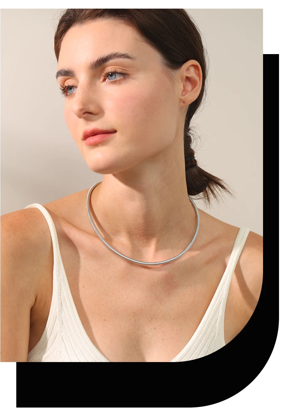 The image shows a person wearing a white sleeveless top and a simple, elegant silver necklace. The person's hair is tied back, and the background is plain, which helps to highlight the necklace. This image is relevant for showcasing the necklace as a fashion accessory, emphasizing its minimalist and stylish design.